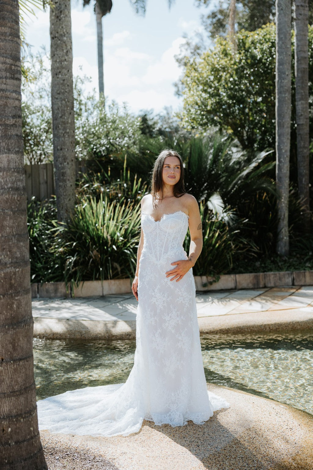 Full length Chiara French lace strapless wedding gown with flowing train in garden